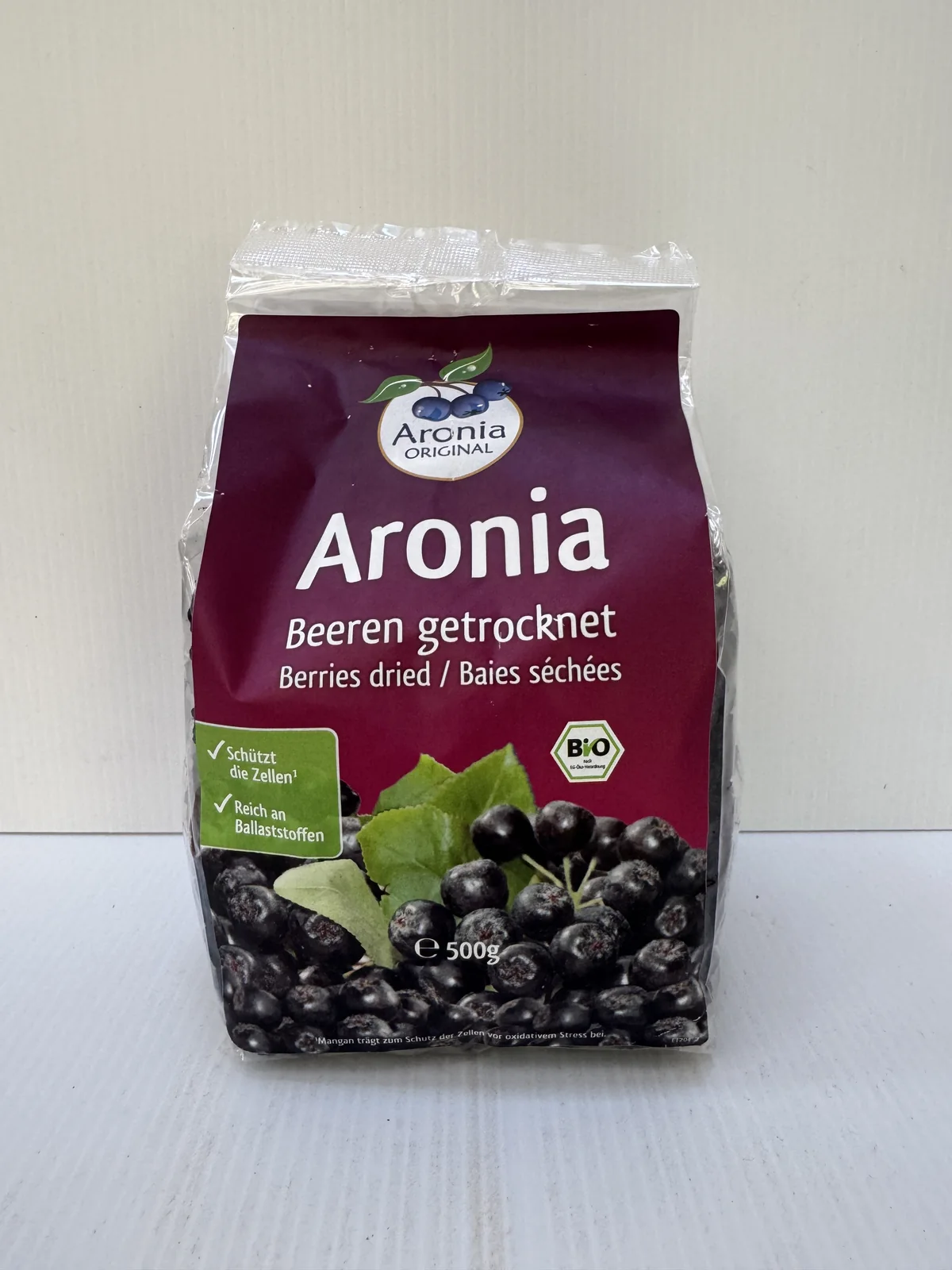 Pose med tørrede aroniabær og en bunke løse bær foran posen.